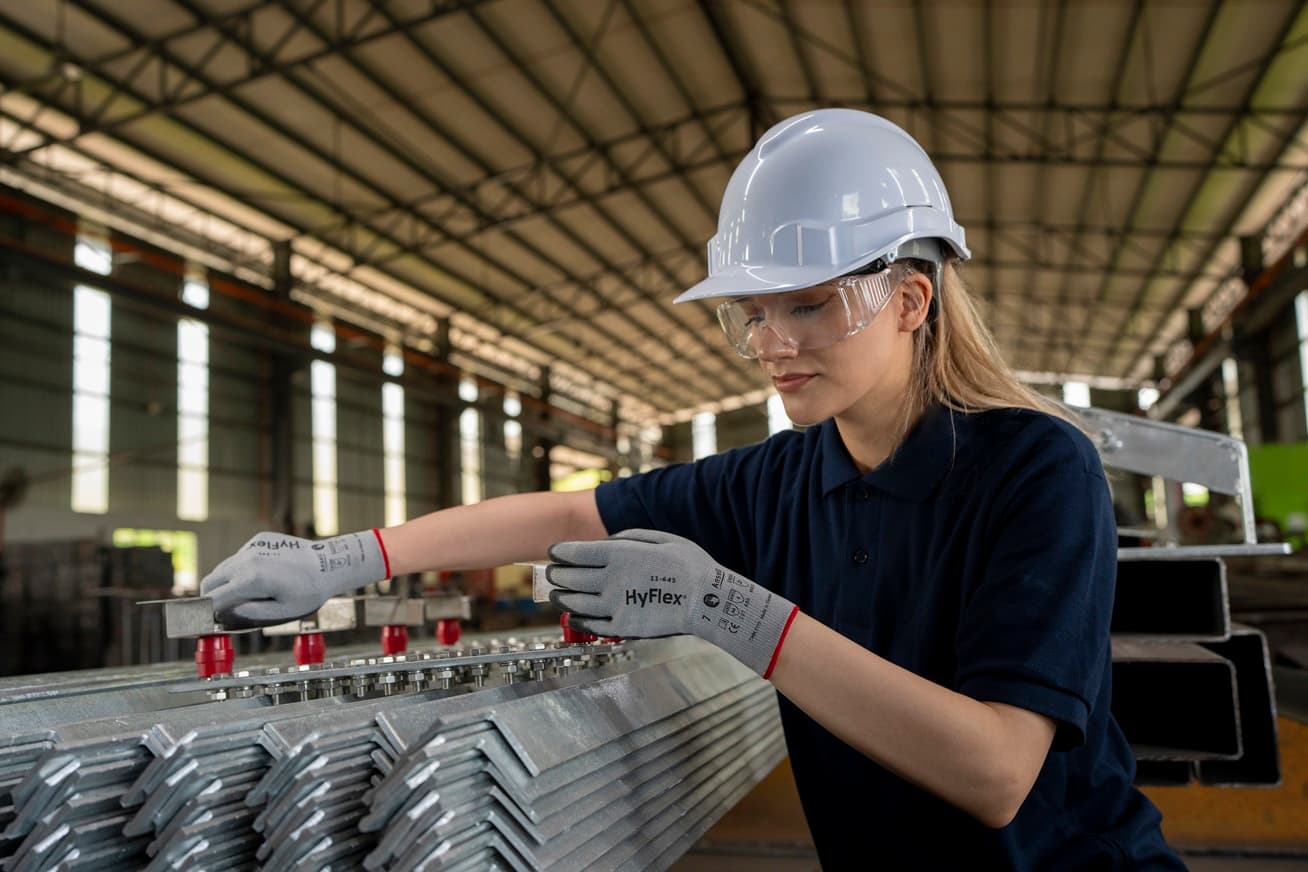 Worker wearing HyFlex® 11-645 mechanical gloves engages in metallurgy tasks, handling metal materials with precision and safety