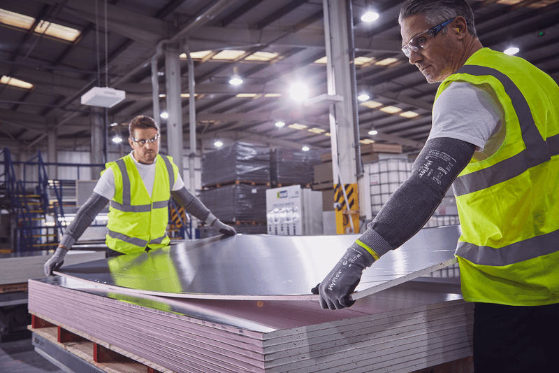 Operators wearing HyFlex® 11-581 mechanical gloves handle a panel, ensuring safe grip and careful positioning during transport