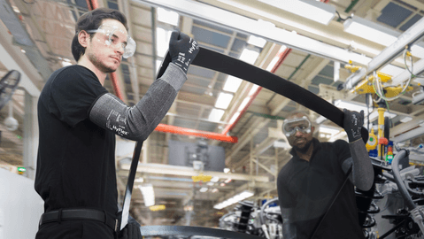 Workers wearing HyFlex® 11-280 sleeves assemble car parts, ensuring safety and precision in the automotive assembly process.
