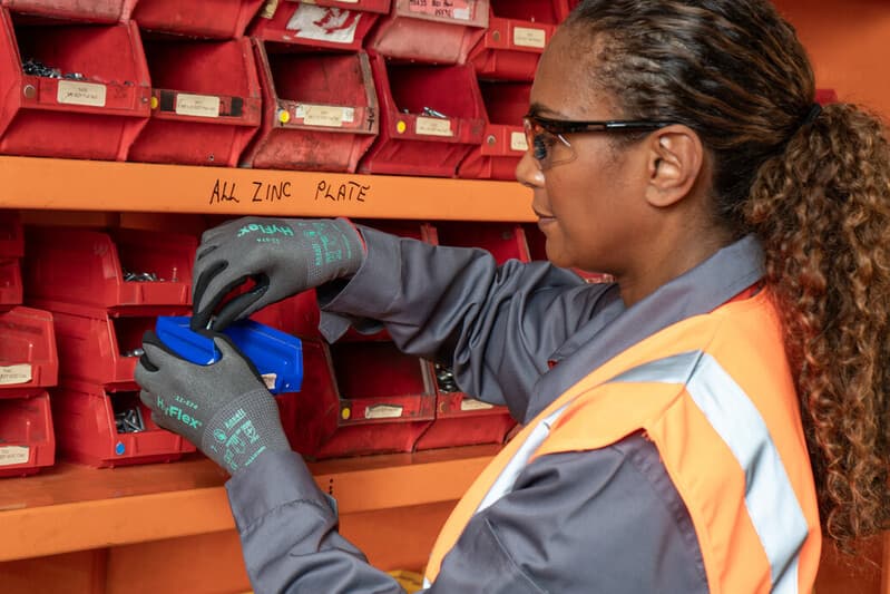 Worker in warehouse handling tasks with HyFlex 11-574 gloves for grip, safety, and dexterity.