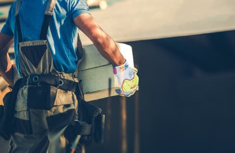 Worker wearing RINGERS® R665 mechanical gloves moves stone pillars, demonstrating strength and safety in construction tasks.