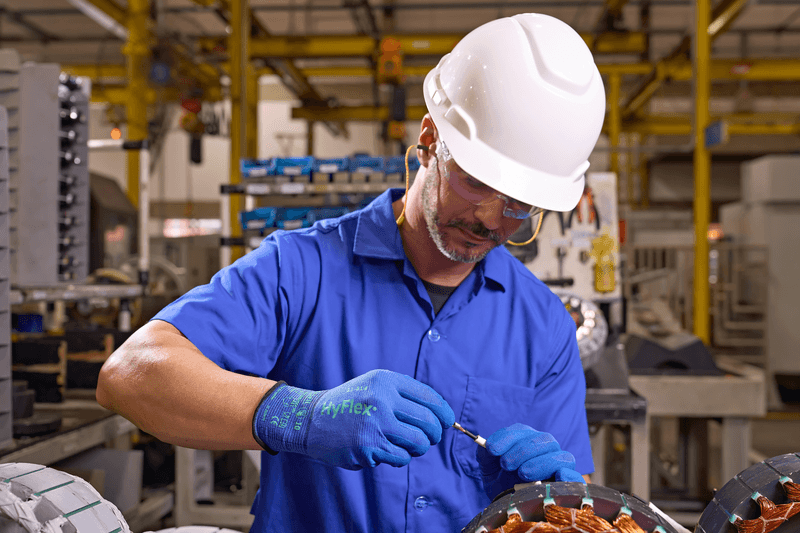Worker assembling small parts while wearing HyFlex 11-814 gloves for precision and protection.