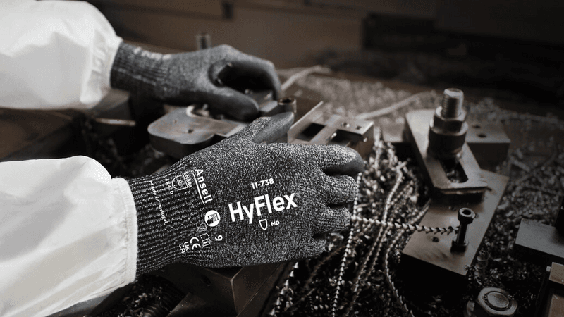 Worker wearing HyFlex 11-738 mechanical gloves, performing maintenance on machinery.