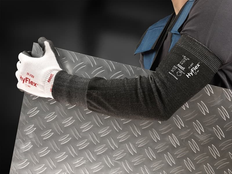 Worker in HyFlex® 11-735 protective gloves and HyFlex® 11-250 sleeves holds a textured metal sheet, ensuring a firm grip while handling heavy materials