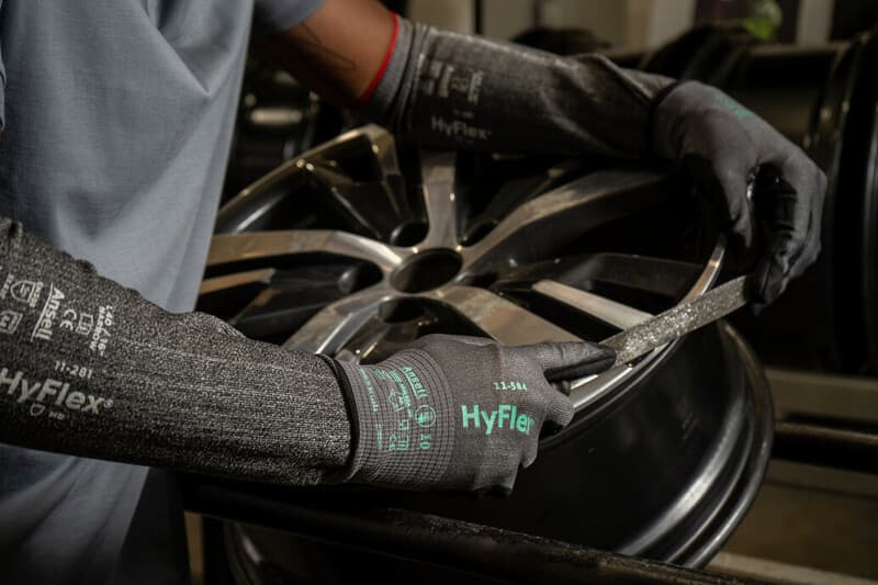 Worker assembling automotive parts with tools while wearing HyFlex 11-584 gloves for cut protection.