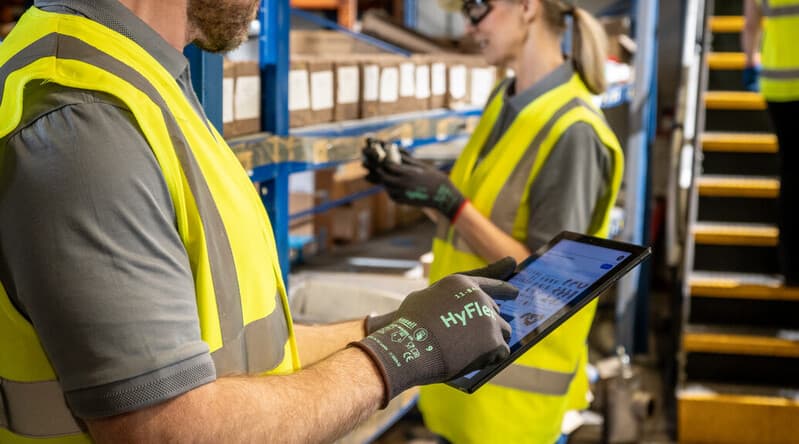 Worker in warehouse handling tasks with HyFlex 11-844 gloves for grip, safety, and dexterity.