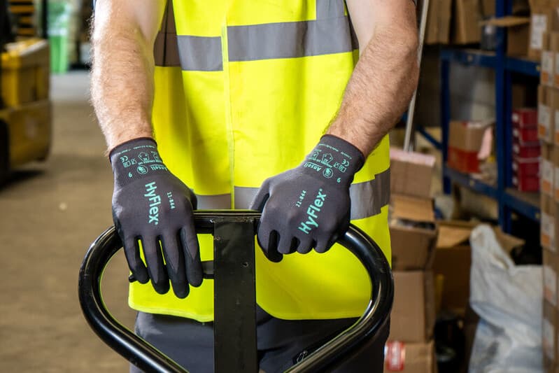 Worker in warehouse handling tasks with HyFlex 11-844 gloves for grip, safety, and dexterity.