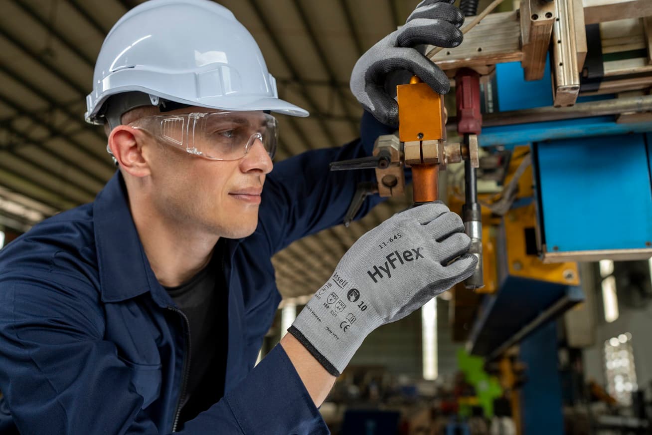 Worker wearing HyFlex® 11-645 mechanical operates on machinery, ready for industrial or repair tasks