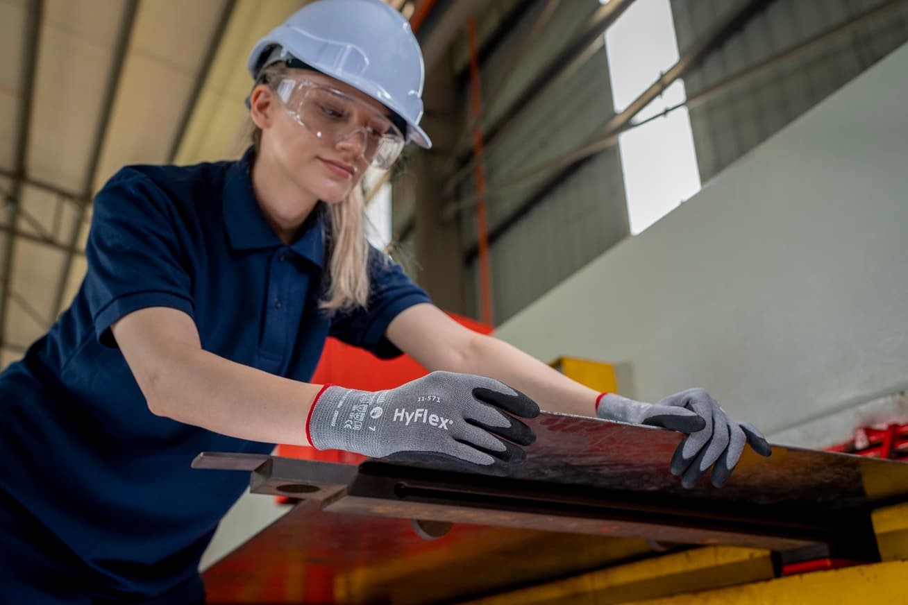 Worker prepares a metal sheet for cutting, using HyFlex® 11-571 mechanical gloves for grip and safety