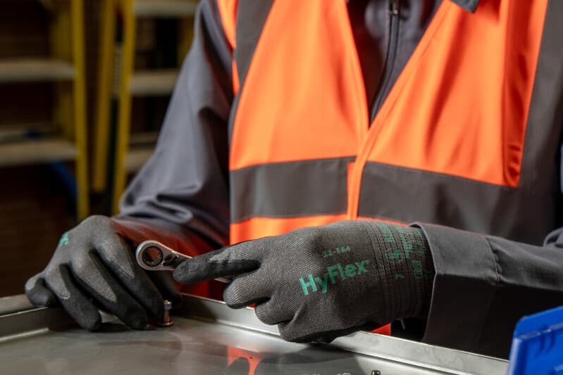 Worker assembling small parts with tools while wearing HyFlex 11-584 gloves for safety and control.