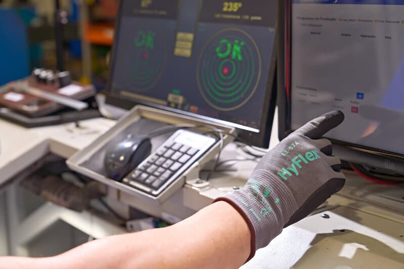 Worker in warehouse using tablet while wearing HyFlex 11-574 touchscreen gloves for safe, precise input.