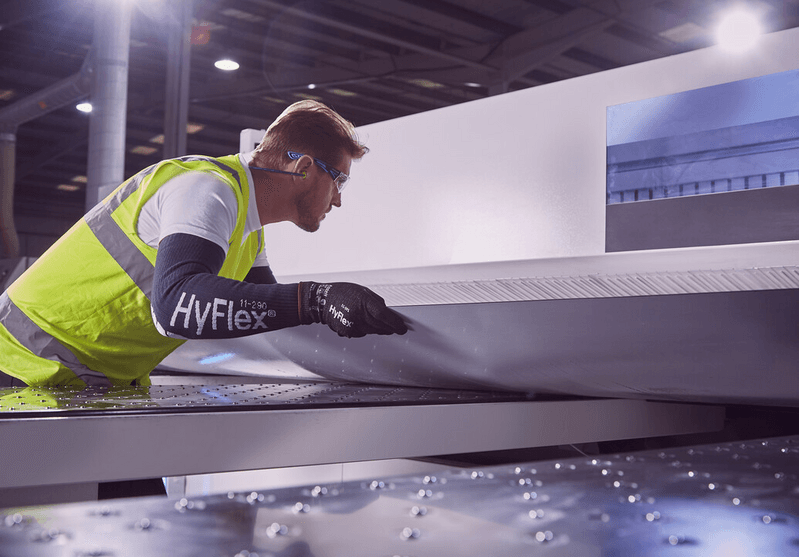 Operator wearing HyFlex® 11-591 mechanical gloves handles a panel, ensuring safe grip and careful positioning