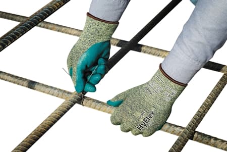 Worker wearing HyFlex® 11-501 mechanical gloves assembles grids with precision, ensuring safety and accuracy in the process.