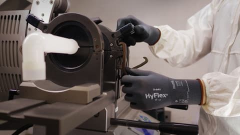 A worker wearing protective clothing and HyFlex 11-840 mechanical glove adjusts knobs and components.