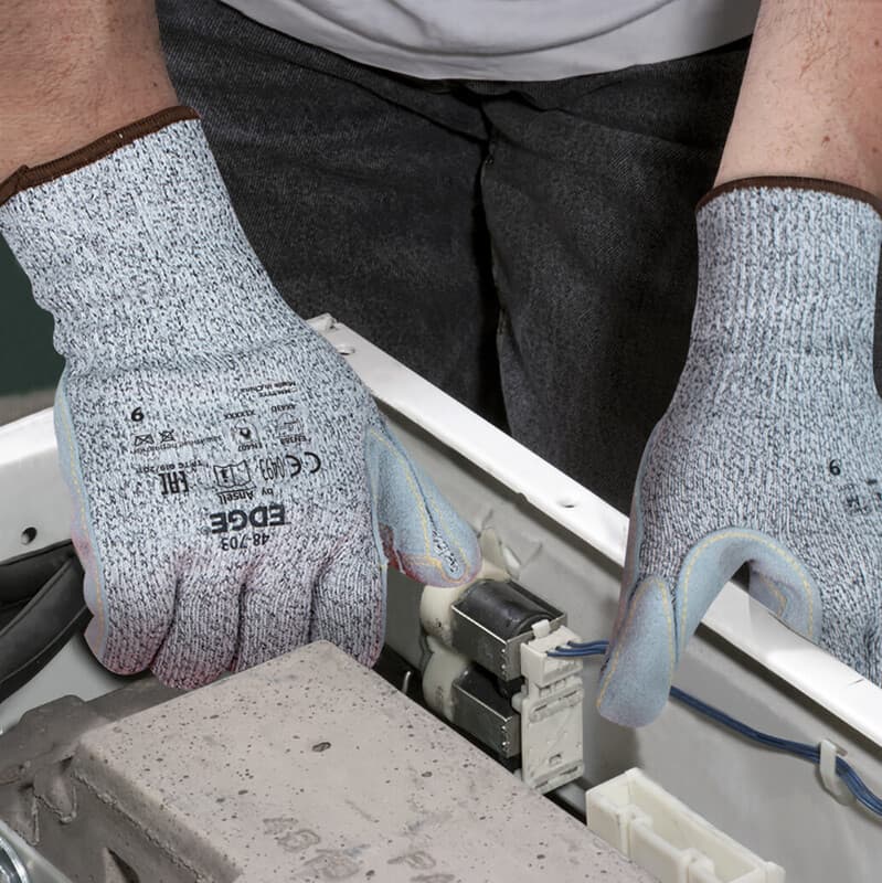 Hands wearing EDGE® 48-703 mechanical gloves working on machinery components
