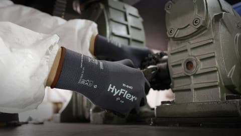 A worker wearing protective clothing and HyFlex 11-840 mechanical glove adjusts knobs and components.
